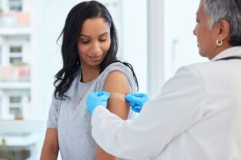 woman-getting-vaccination a woman getting a shot to make sure she meets the vaccination requirements for traveling abroad