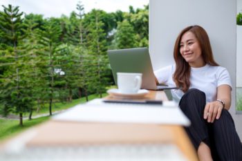 A woman covered by digital nomad insurance enjoys remote work on her laptop, sitting on a balcony with a lush green view. A woman covered by digital nomad insurance enjoys remote work on her laptop, sitting on a balcony with a lush green view.