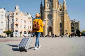 tourist-in-spain a woman pulling a suitcase along a square in Spain, having researched does my health insurance cover international travel