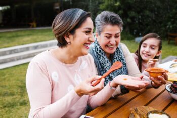 health-insurance-greek-expats two Greek women and a young girl preparing food outside having secured health insurance for Greek expats