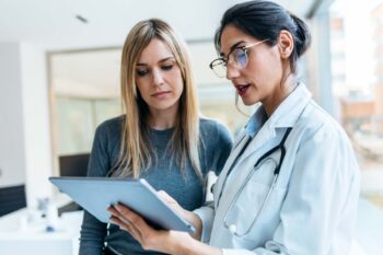 healthcare-costs-in-the-us a female patient talking to a doctor and looking at a clipboard