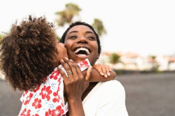 caribbean-woman-with-child a happy Bahamian woman smiling and hugging her child, safe in the knowledge that she has insurance for Bahamian citizens