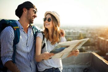 young-couple-traveling-with-a-map A young couple with backpacks smiling while holding a map, symbolizing the peace of mind and freedom that comes with single-trip travel insurance coverage