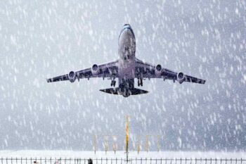 plane-flying-in-snow A passenger plane taking off during a snowstorm, with a travel advisory in effect due to hazardous weather conditions