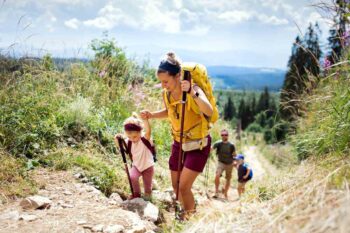 family-hiking-on-vacation A husband and wife hiking with two young children happily talk about their decision to buy international health insurance.