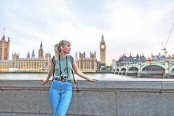 female-tourist-in-london a young female tourist posing In front of the Palace of Westminster in London, having purchased UK travel insurance for her trip