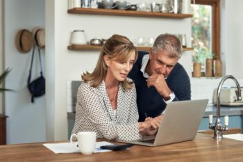 a couple on a laptop in a kitchen, researching how coverage choices impact insurance premiums