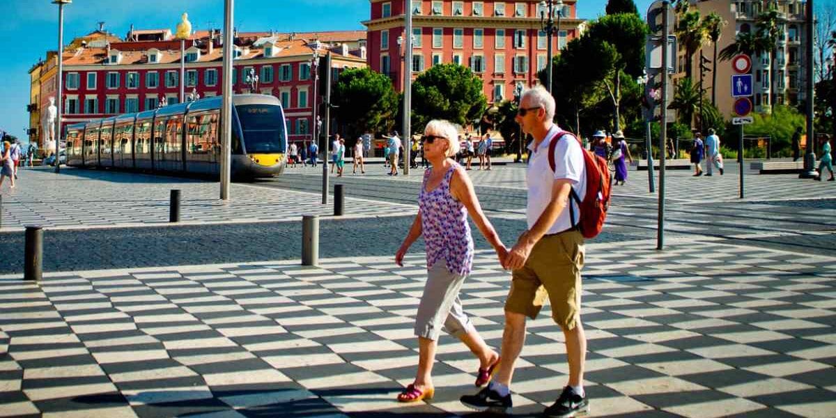 a senior couple walking through Place Massena in Nice, after buying travel insurance for France