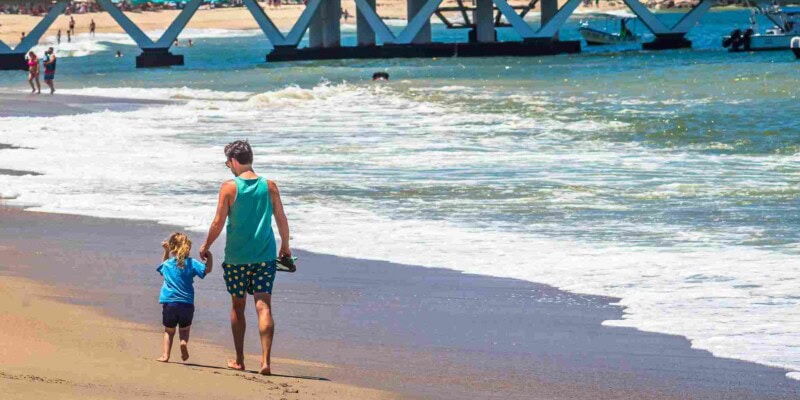 a father and son walking along a beach in Mexico, one of the best countries to move to from the USA with family