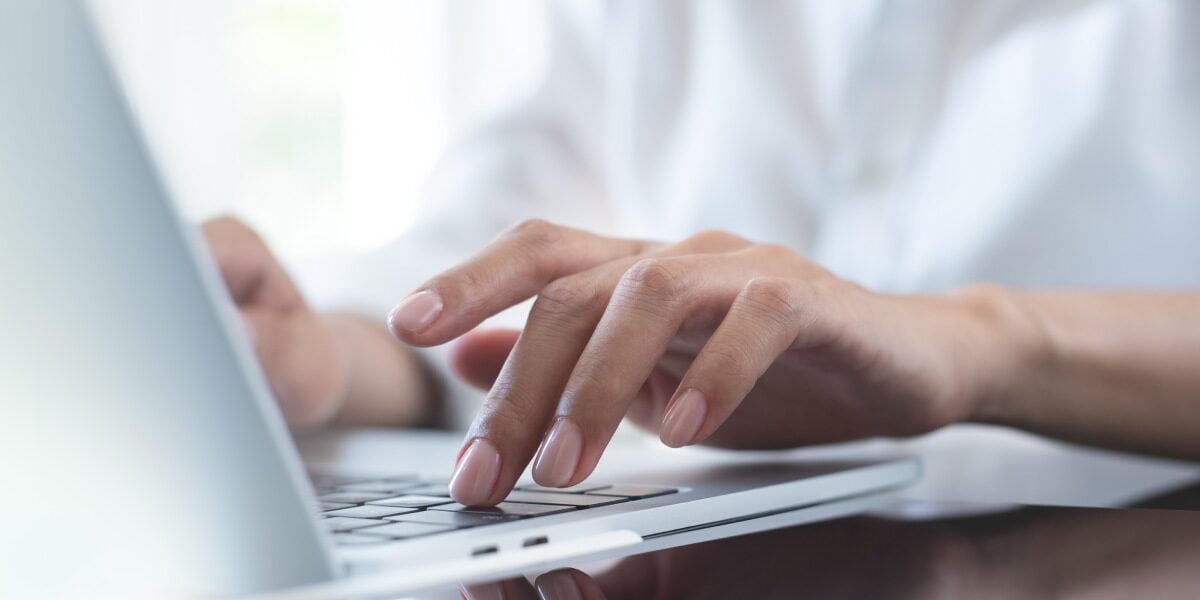 a close-up of hands typing on a laptop keyboard, showing how an international PEO can enable employees to work remotely
