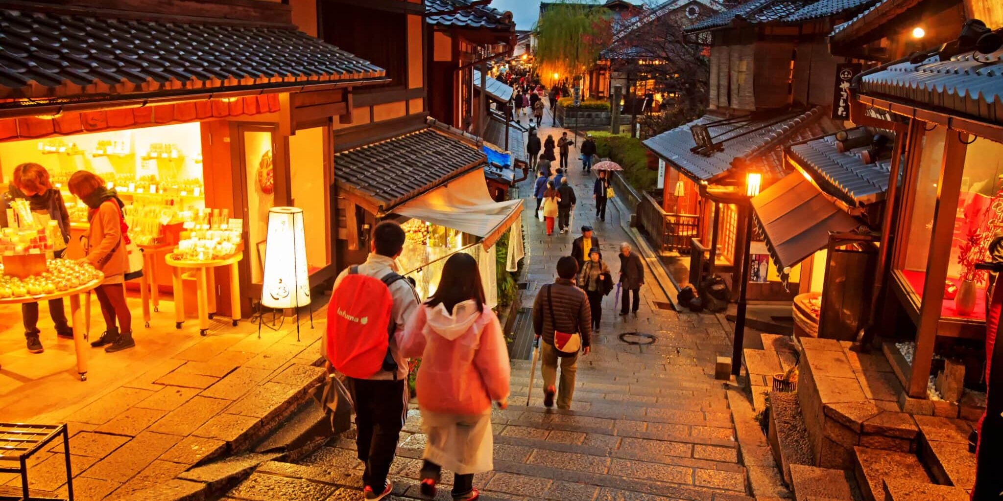 Tourists at Kiyomizu Temple Japan two tourists walking down a slope in Kyoto at night, indicating the importance of securing travel insurance for Japan