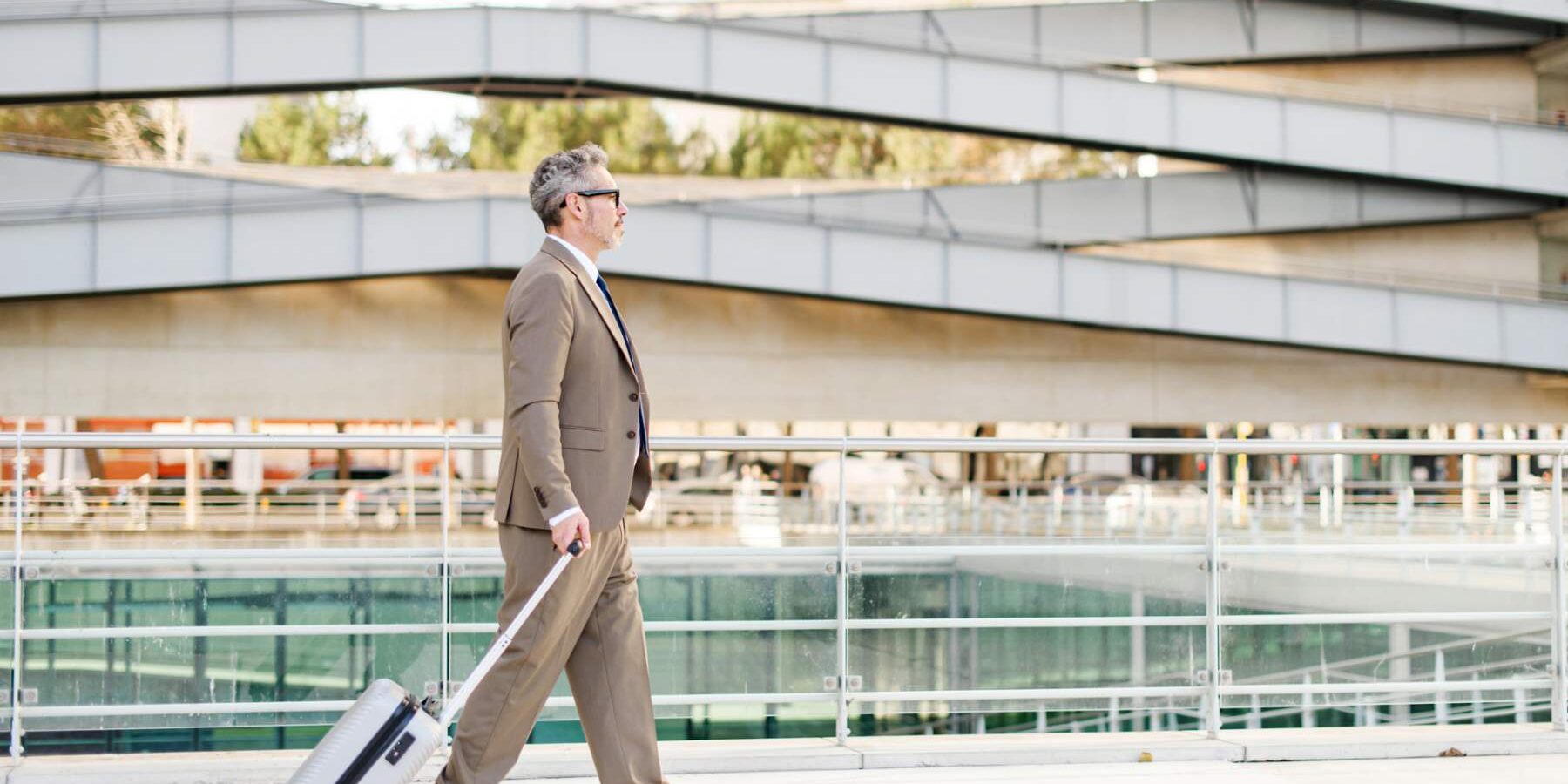 business-man-in-airport a seasoned businessman walking purposefully with a rolling suitcase in a clean, empty airport