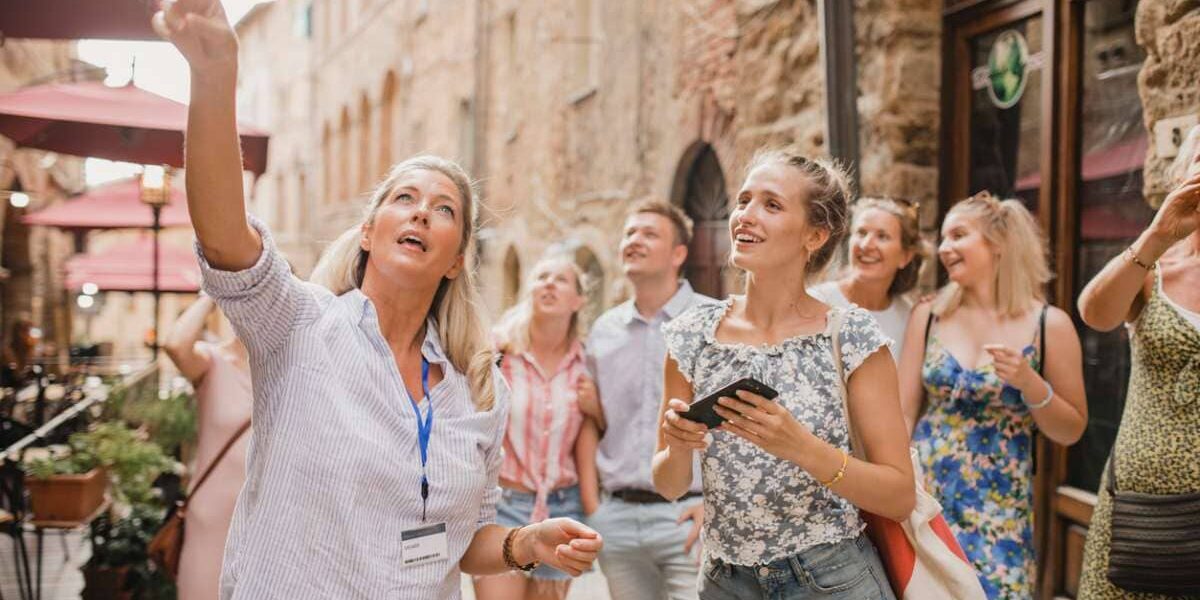 city-tour-guide A female tour guide leading a group of tourists, showing them a local building