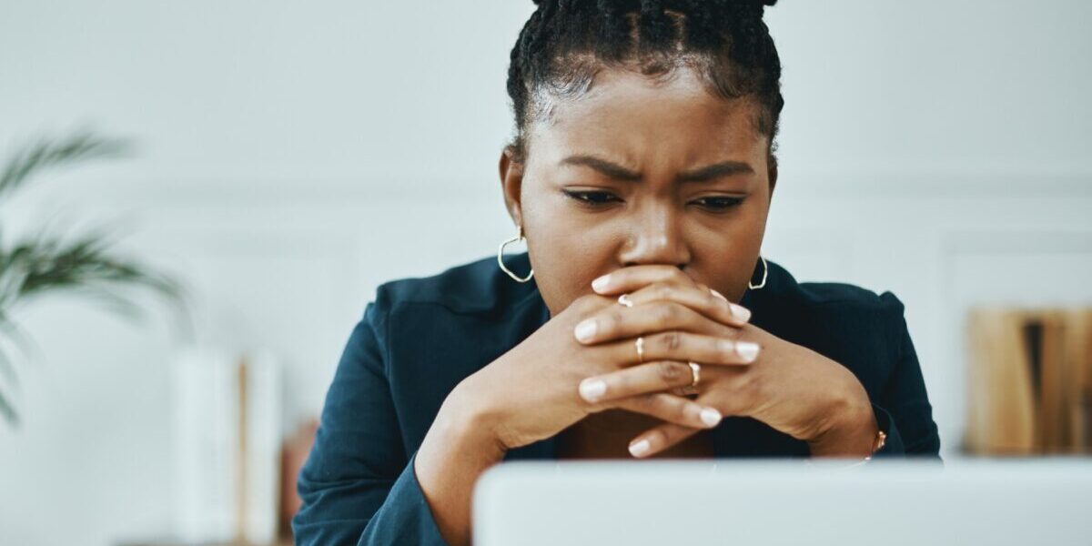 concerned-woman-on-laptop a woman frowning and looking concerned as she looks down at her laptop, reading safety tips for avoiding terrorism attacks