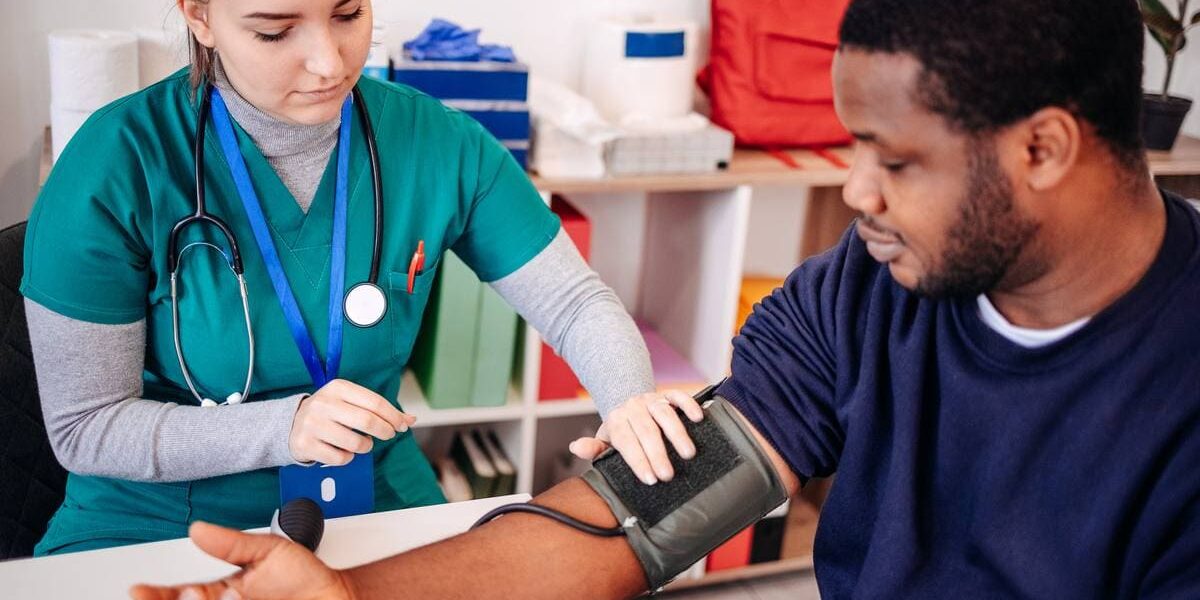 doctor-with-patient a medical assistant checking a young patient's blood pressure, indicating the importance of securing student group travel insurance for trip abroad and weighing up whether to buy travel insurance vs health insurance
