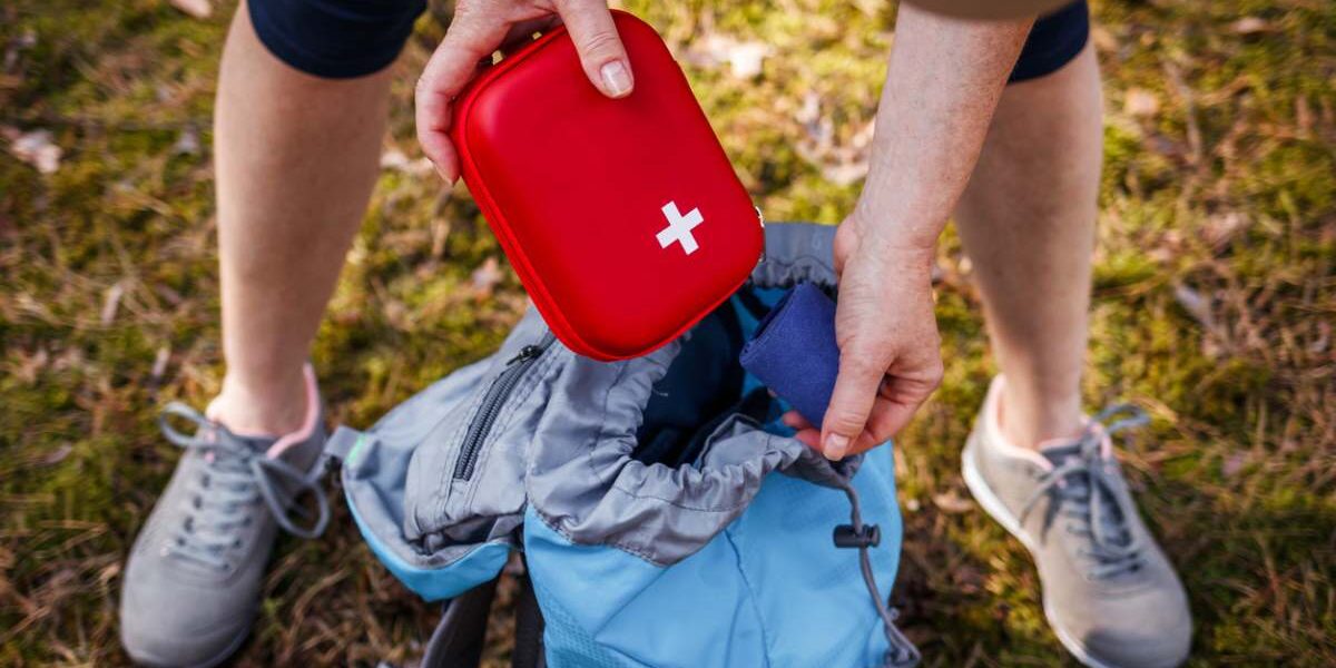 emergency-kit A hiker taking out a first aid kit from their backpack