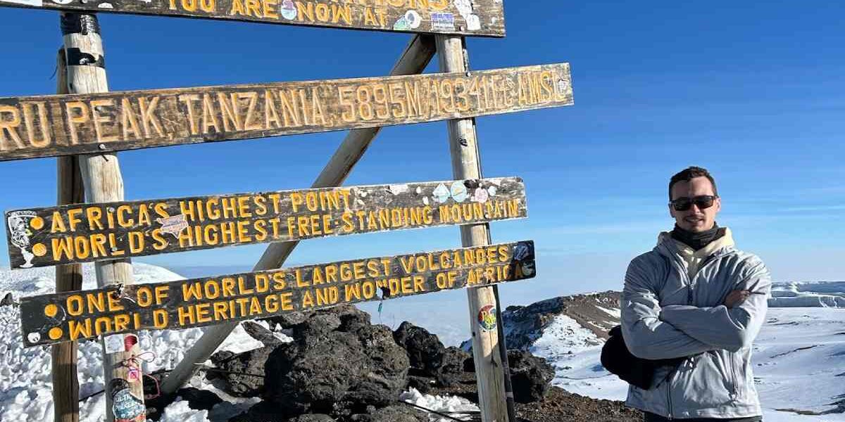 summit-mount-kilimanjaro A climber standing at the summit of Mount Kilimanjaro during his adventure travel experience