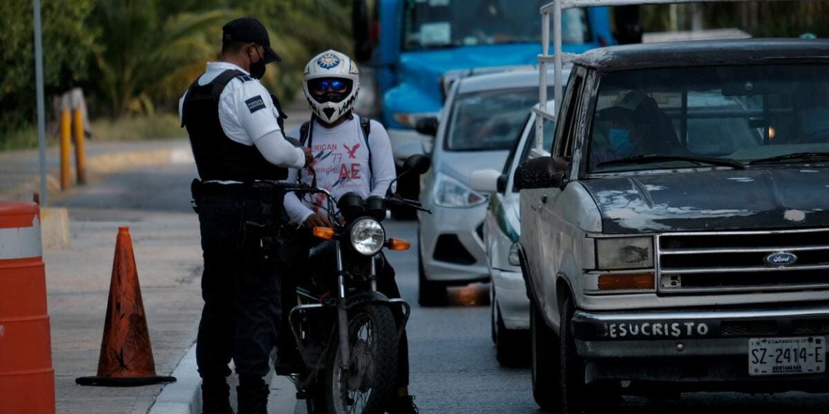 traffic-police-mexico a policeman checking a motorcyclist's paperwork on the side of a busy road in Mexico
