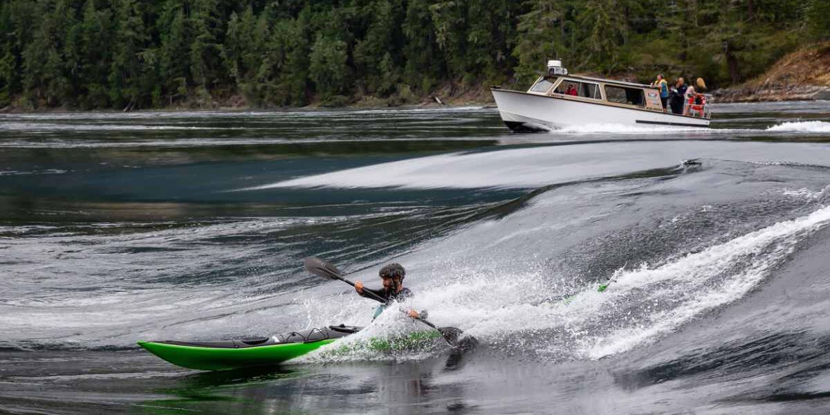 whitewater-kayaking an adventurous tourist on a whitewater kayak riding a standing wave in Canada, highlighting the importance of buying travel insurance for Canada