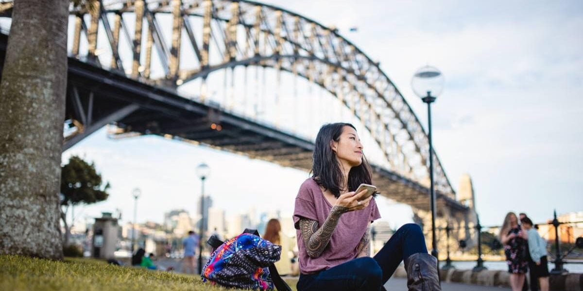 woman-by-sydney-harbour-bridge A woman relaxing by Sydney Harbour Bridge in Australia, one of the best countries to live in as an expat