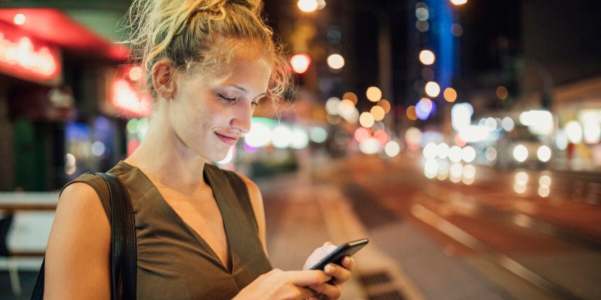 woman-on-cell-phone a woman booking an Uber on her cell phone at night