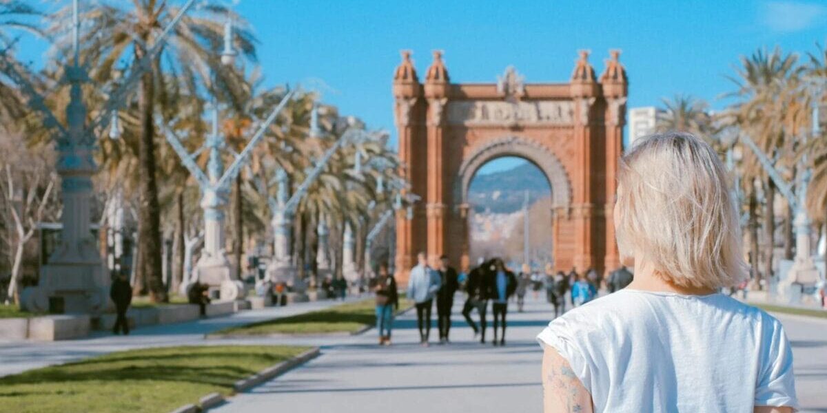 woman-walking-in-spain a woman standing in front of a landmark archway in Spain
